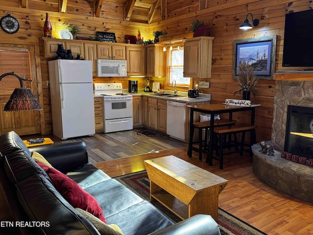 kitchen featuring vaulted ceiling with beams, wood walls, a sink, wood finished floors, and white appliances