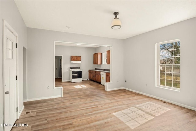 unfurnished living room with light wood finished floors, visible vents, and baseboards