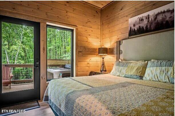 bedroom featuring access to exterior, wooden walls, and wood finished floors