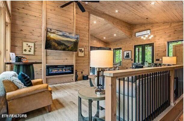 living area featuring a glass covered fireplace, wood ceiling, an AC wall unit, wooden walls, and wood finished floors