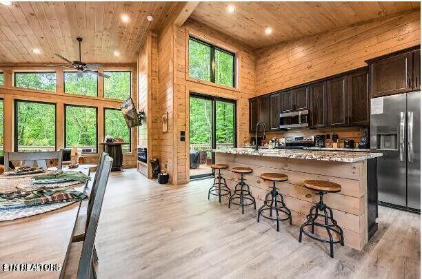 kitchen featuring a breakfast bar area, wooden ceiling, stainless steel appliances, a high ceiling, and light wood-type flooring