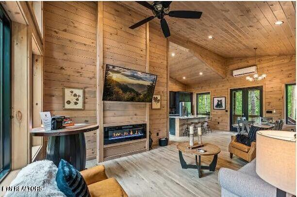 living area with wooden walls, wood finished floors, wood ceiling, an AC wall unit, and a glass covered fireplace