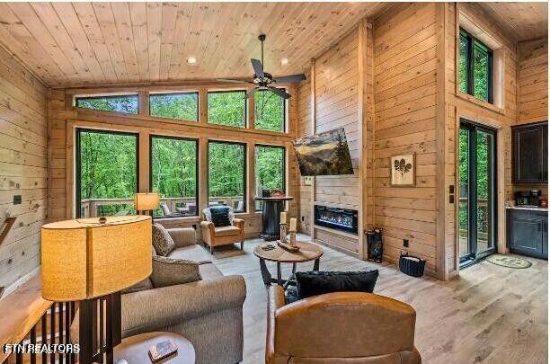 living area with a fireplace, wood ceiling, and wooden walls