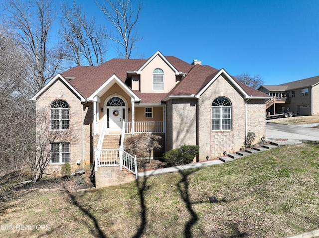 view of front of property with a shingled roof, a chimney, a front lawn, and brick siding