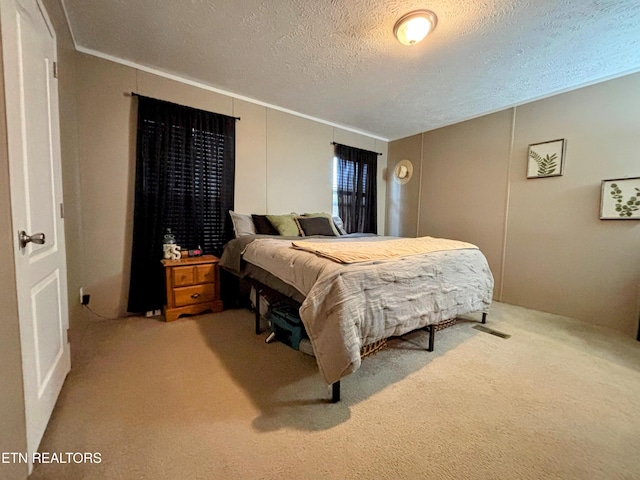 bedroom featuring crown molding, a textured ceiling, and light colored carpet