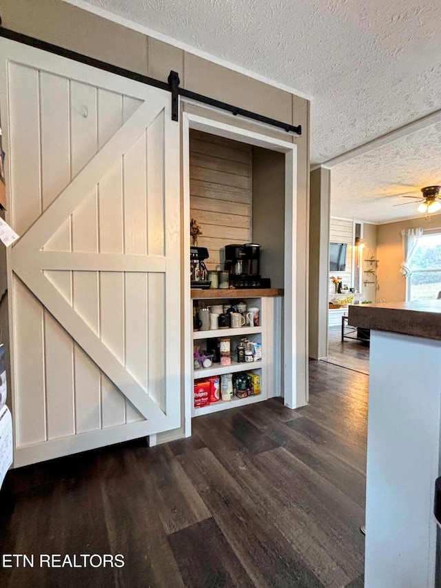 interior space featuring a barn door, a textured ceiling, ceiling fan, and wood finished floors