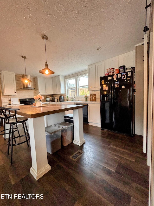 kitchen featuring butcher block countertops, visible vents, white cabinets, dark wood-style floors, and black appliances