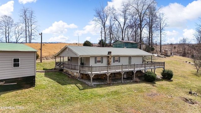 rear view of house with metal roof, a lawn, and a wooden deck