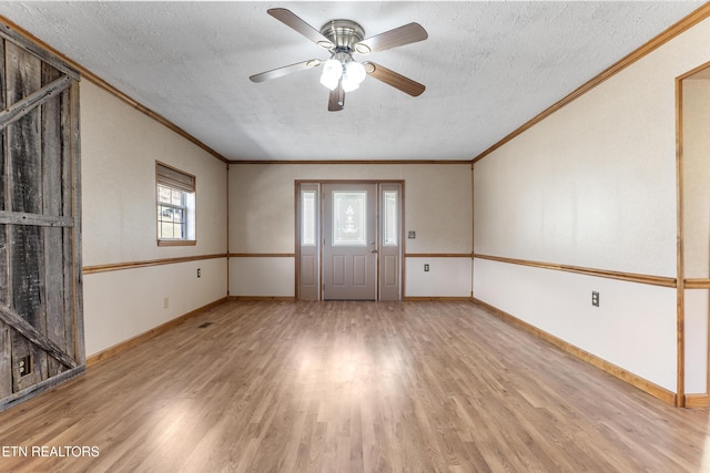spare room with crown molding, a textured ceiling, baseboards, and wood finished floors