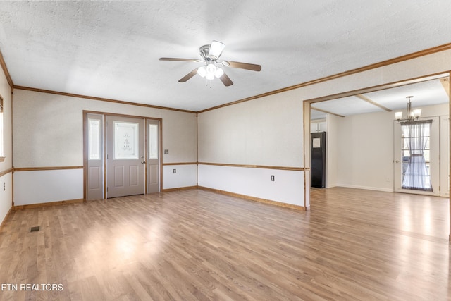 unfurnished room featuring a textured ceiling, ceiling fan with notable chandelier, baseboards, ornamental molding, and light wood-type flooring
