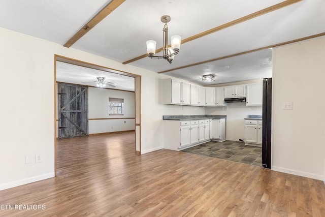 kitchen featuring dark wood-style floors, open floor plan, under cabinet range hood, white cabinetry, and beam ceiling