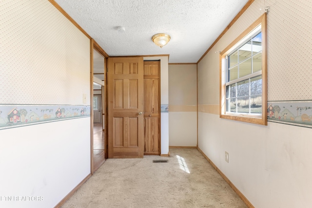 corridor with carpet flooring, a textured ceiling, and wallpapered walls
