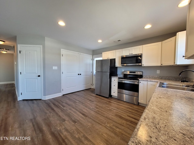 kitchen featuring white cabinets, appliances with stainless steel finishes, dark wood finished floors, and a sink