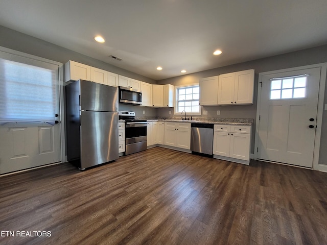 kitchen with dark wood-style floors, recessed lighting, a sink, white cabinets, and appliances with stainless steel finishes