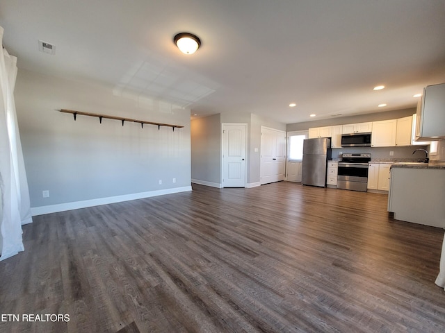 kitchen featuring baseboards, dark wood finished floors, open floor plan, stainless steel appliances, and white cabinetry