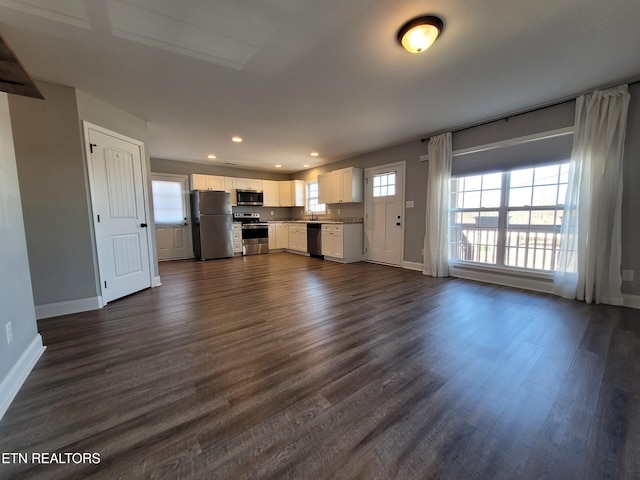 unfurnished living room featuring a wealth of natural light, baseboards, dark wood-type flooring, and recessed lighting