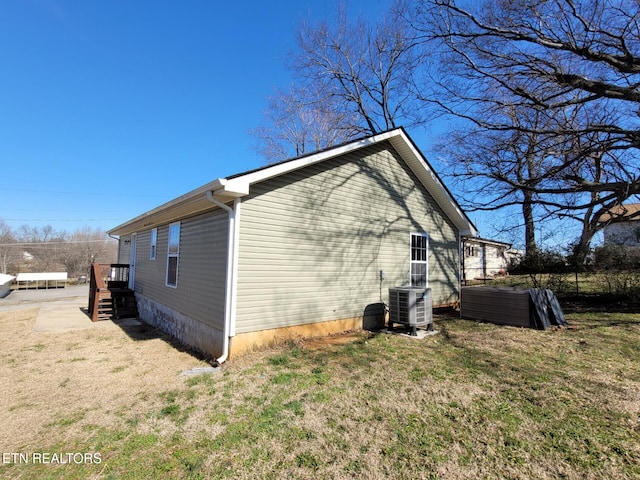 view of side of property featuring central AC unit and a yard