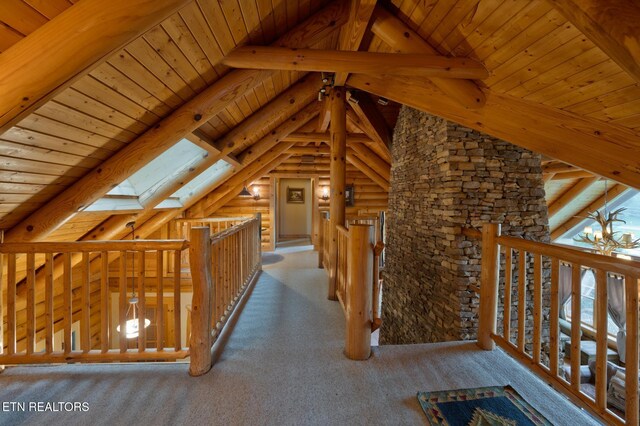 hall featuring carpet, wood ceiling, vaulted ceiling with skylight, and an upstairs landing