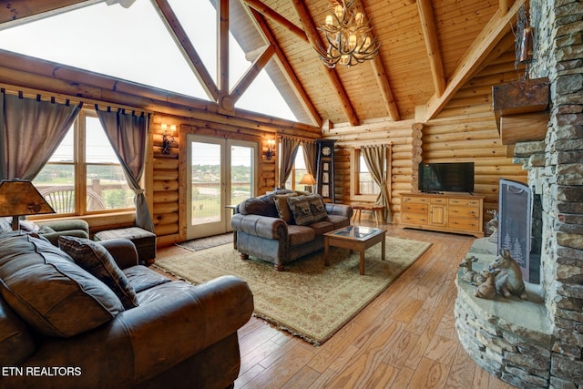 living area with a stone fireplace, a notable chandelier, french doors, beam ceiling, and light wood finished floors