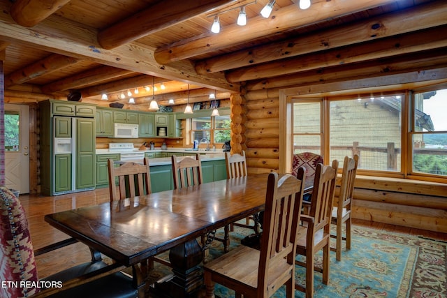 dining space featuring log walls, light wood-style floors, track lighting, wooden ceiling, and beamed ceiling