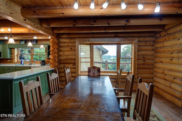 dining space with plenty of natural light, beam ceiling, log walls, and wood finished floors