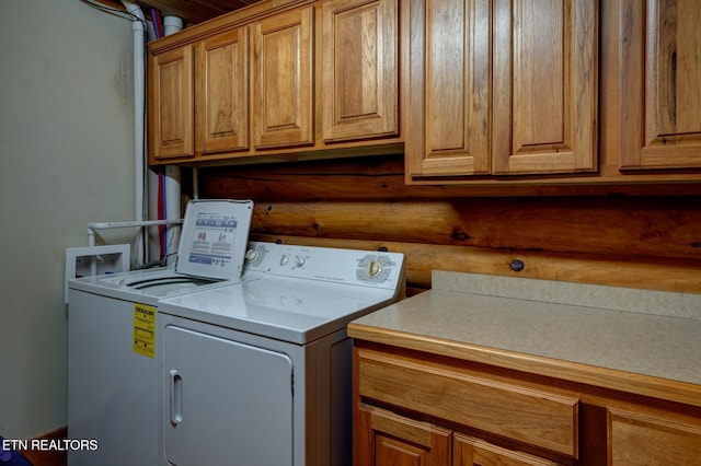 washroom with cabinet space, log walls, and washing machine and clothes dryer