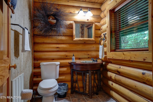 bathroom with toilet, visible vents, log walls, and vanity