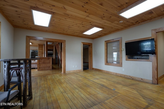 interior space featuring ornamental molding, wooden ceiling, light wood-style flooring, and baseboards