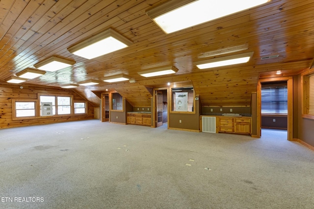 unfurnished living room featuring light carpet, wooden walls, visible vents, and vaulted ceiling