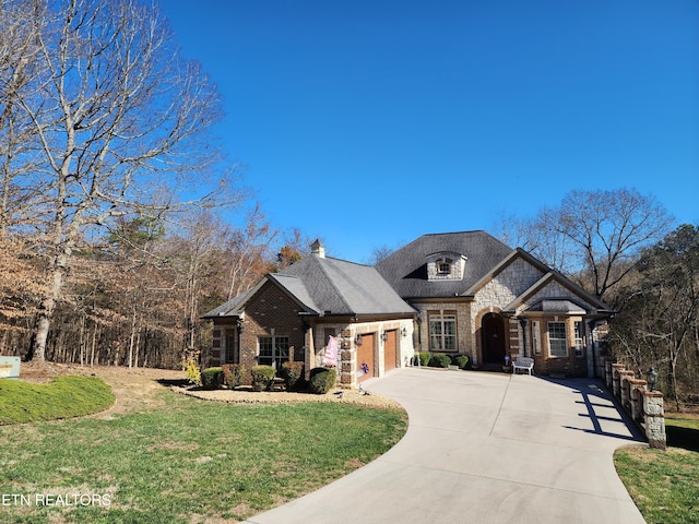 french country style house with brick siding, concrete driveway, a front yard, stone siding, and an attached garage