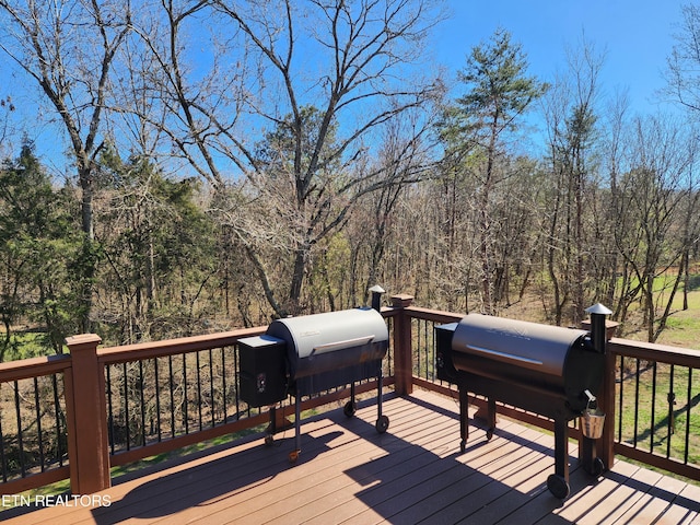 deck with area for grilling and a wooded view