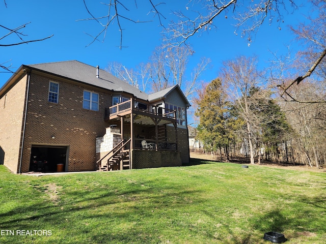 back of house with a yard, brick siding, a wooden deck, and an attached garage