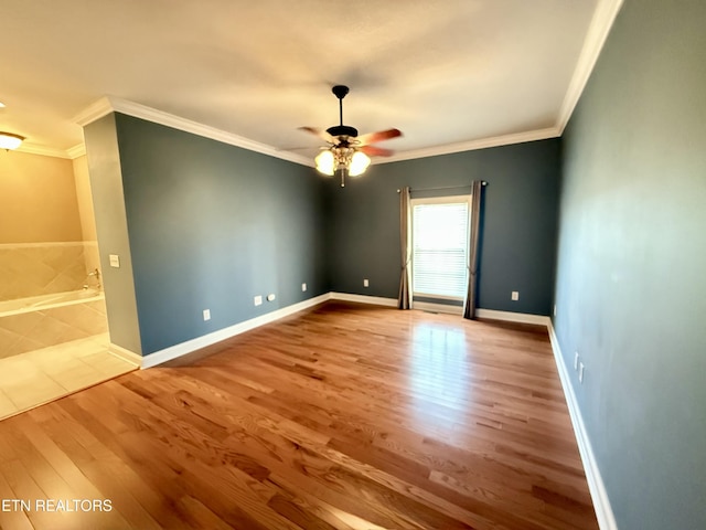 empty room featuring a ceiling fan, crown molding, baseboards, and wood finished floors