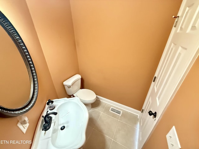 half bathroom with toilet, baseboards, visible vents, and tile patterned floors