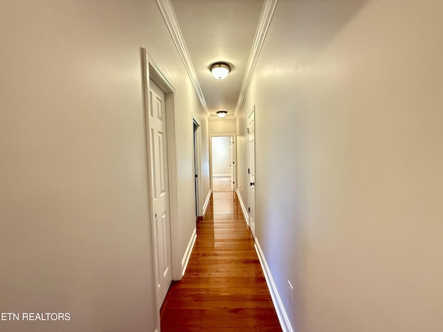 hallway featuring ornamental molding, baseboards, and wood finished floors