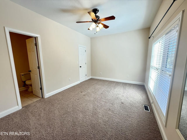 unfurnished bedroom featuring visible vents, baseboards, connected bathroom, ceiling fan, and carpet