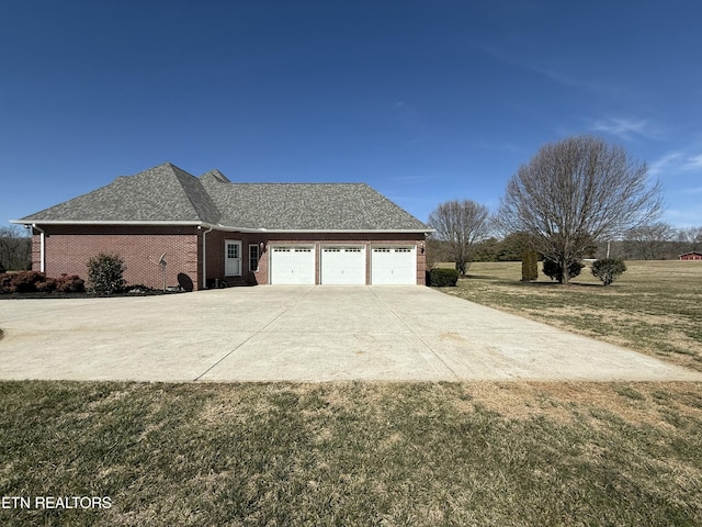 view of side of property with brick siding, a yard, a shingled roof, concrete driveway, and an attached garage