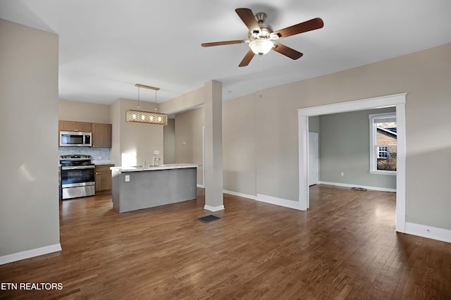 kitchen with stainless steel appliances, light countertops, backsplash, dark wood-type flooring, and open floor plan