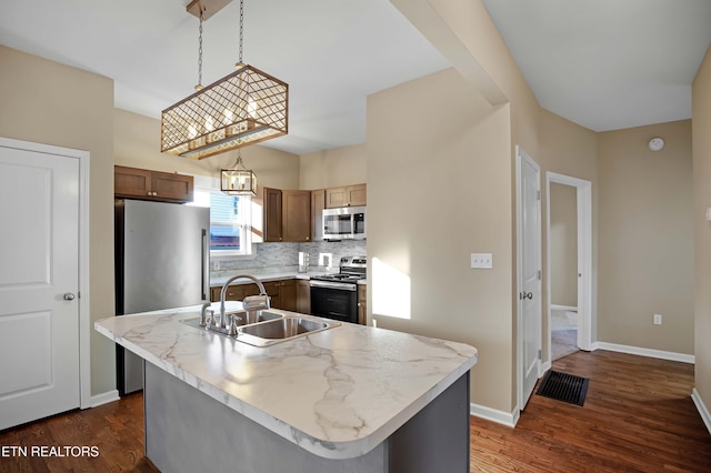 kitchen featuring appliances with stainless steel finishes, dark wood-type flooring, a sink, light countertops, and backsplash