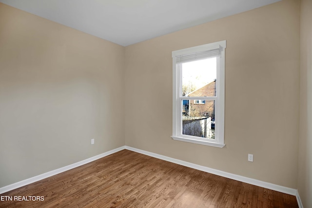 unfurnished room with baseboards and dark wood-style flooring