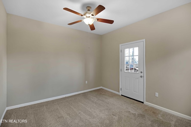 carpeted spare room with a ceiling fan and baseboards