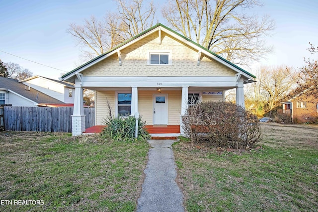 bungalow with covered porch, fence, and a front yard