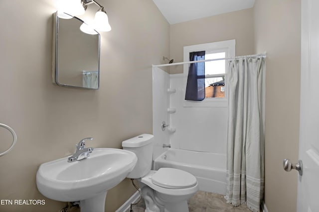 bathroom featuring a sink, shower / bath combo with shower curtain, and toilet