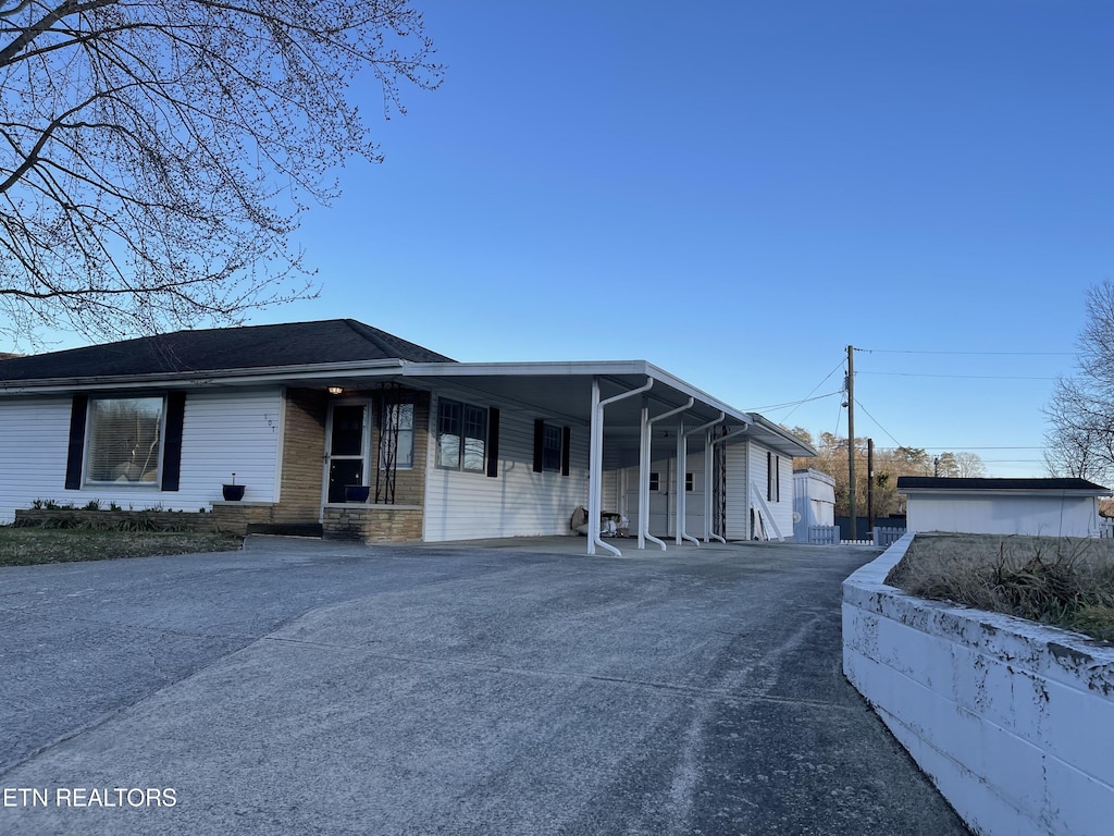 view of front of house with a carport, stone siding, and driveway