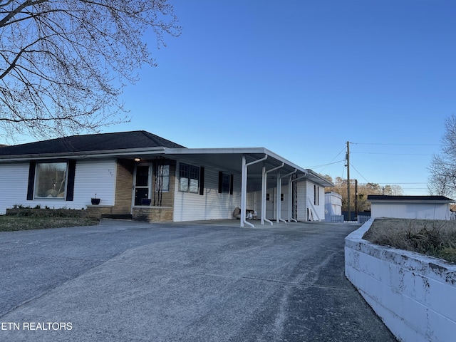 view of front of house with a carport, stone siding, and driveway