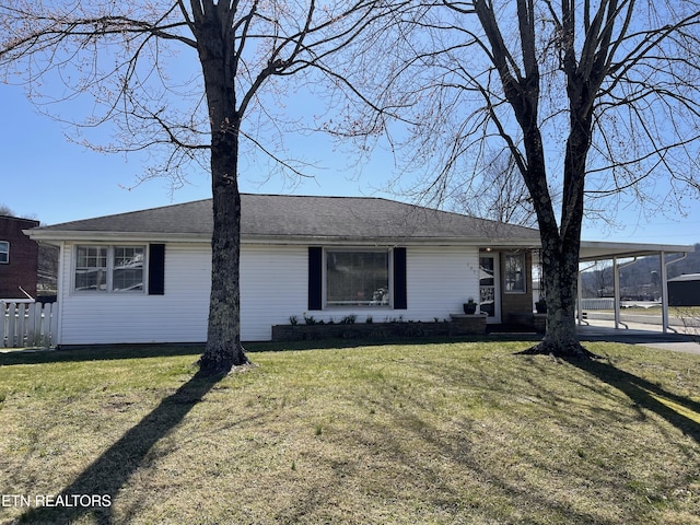 view of front of house with an attached carport, a front yard, and fence