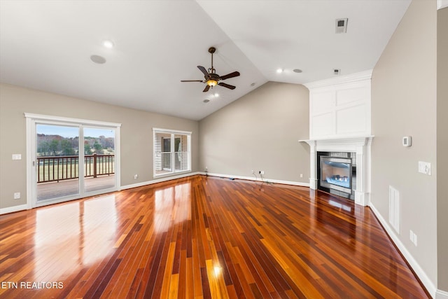 unfurnished living room with lofted ceiling, a tile fireplace, visible vents, baseboards, and hardwood / wood-style floors