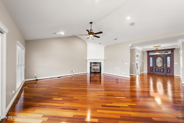 unfurnished living room with a glass covered fireplace, vaulted ceiling, baseboards, and wood finished floors