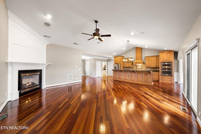 living room featuring vaulted ceiling, dark wood-type flooring, a glass covered fireplace, and visible vents