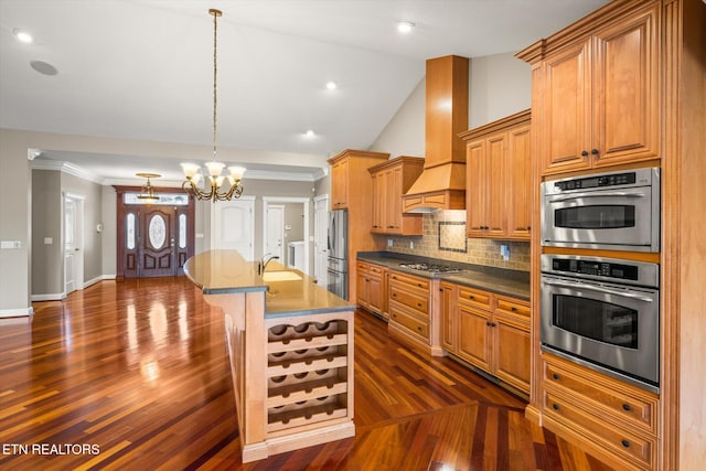 kitchen featuring crown molding, stainless steel appliances, lofted ceiling, tasteful backsplash, and wall chimney range hood